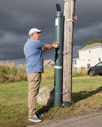 Brett Branco stands at a FloodNet sensor in Hamilton Beach, Queens.