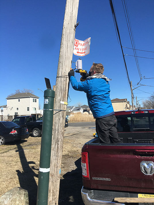 Researchers install one of the FloodNet sensors.